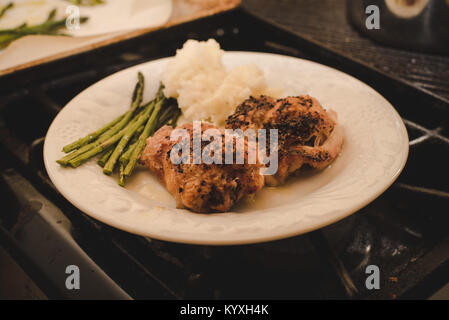 `A dinner plate with rice, asparagus, and chicken cooked in an oven sitting on a stove. Stock Photo